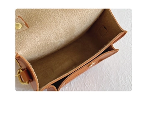 Gros plan d'un sac en cuir marron avec compartiment intérieur et bouton-pression doré