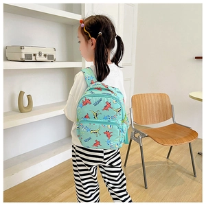 Detail view of mint green canvas backpack with dinosaur prints worn by a child model