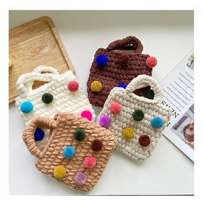 Detail of four chunky knit bags in neutral tones with colorful plush pom-poms