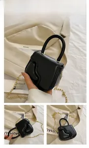 Detail of black mini handbag featuring 3D wave texture and detachable gold chain strap