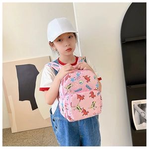 Pink toddler backpack with cartoon dinosaur prints shown on child model in soft light