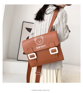 Detail of a brown PU leather backpack featuring a cute white bear and Stay Cute text