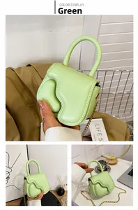 Detail view of light green mini handbag with irregular flap and gold chain strap