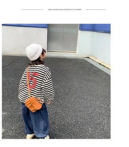 Détail du petit sac cartable orange avec double boucle porté en bandoulière par un enfant