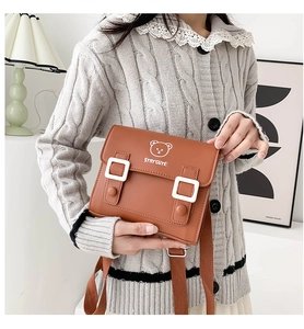 Detail of a brown PU leather children's backpack with cute bear print and white buckles