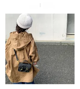 Vue de dos d'un enfant portant un sac messager vintage en cuir noir avec boucles