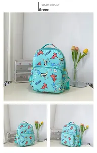 Close-up of green kids backpack with cartoon dinosaur prints and front zipper pocket