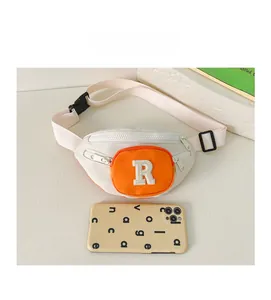 Mini canvas chest bag with orange R patch showing size comparison to a smartphone