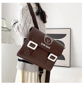 Detail showing the brown PU leather messenger bag with Stay Cute bear print on a model