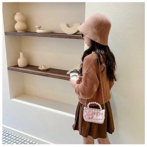 Close-up of pink tweed girl's bag with pearl handle, floral decor, and Barbie embroidery