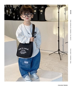 Close-up of a child's trendy black canvas crossbody bag with white letter printing