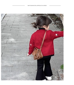 Détail d'un mini sac bandoulière vintage en cuir marron avec un cardigan rouge pour fille
