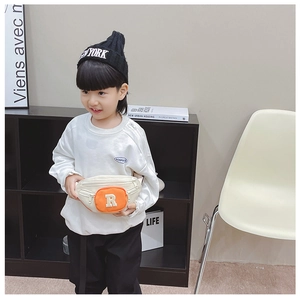 Child wearing a stylish cream canvas chest bag with a small orange letter R pocket
