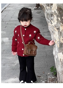 Détail du cardigan rouge brodé et d'un petit sac à bandoulière en cuir marron