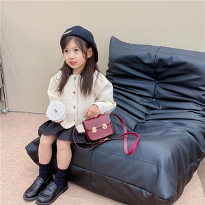 Fille en cardigan beige et jupe noire avec un petit sac à bandoulière vintage en cuir PU rouge
