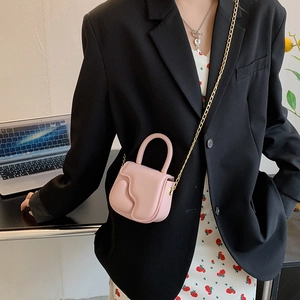 Pink heart-embossed mini crossbody bag with gold chain strap shown on a model