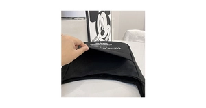 Detail of black canvas shoulder bag showing external pocket design and white typography