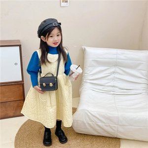 Fille en pull bleu et robe matelassée avec un mini sac carré vintage en cuir PU noir