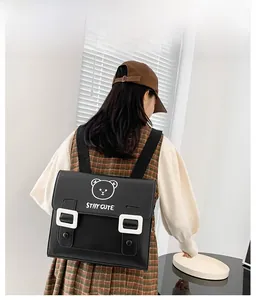 Detail showing the cartoon bear print and magnetic buckle on black PU leather school bag