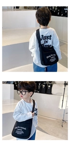 Detail view of a black canvas crossbody bag for kids with white letter printing