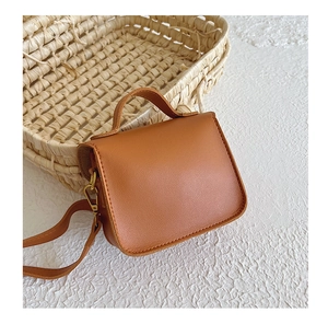 Détail d'un mini sac cartable vintage marron avec poignée et bandoulière à côté du panier