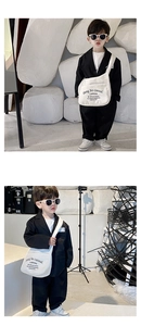 Detail of white canvas kids crossbody bag featuring black letter print and wide strap