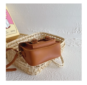 Gros plan d'un mini sac messager vintage marron pour enfants dans un panier tressé
