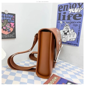Detail of brown PU leather bag featuring a cartoon bear print and canvas strap