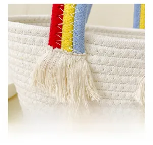 Détail d'un sac panier tressé en coton avec poignées arc-en-ciel et détails de gland