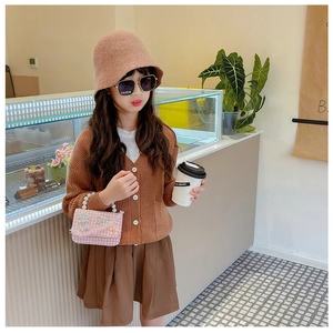 Detailansicht eines Kinderoutfits mit Strickjacke und gewebter Mini-Kettenhandtasche