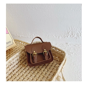 Détail d'un petit sac cartable marron rétro avec boucles dorées dans un panier
