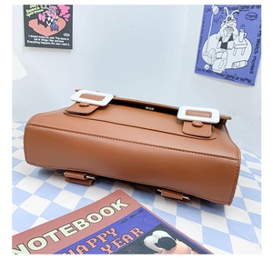 Detailed bottom view of brown PU leather backpack with decorative white buckles