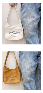 Detail view of canvas cross-body bags in cream and yellow with casual lettering print