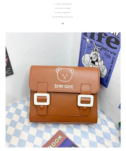 Close-up of brown PU leather bag with cute bear print and large white square buckles