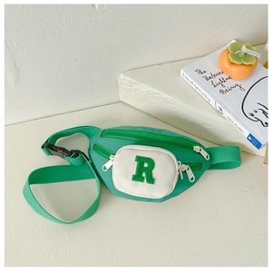 Detail of green nylon kids chest bag with white pocket and plush letter R patch