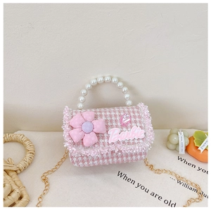 Close-up of pink tweed girl's purse with pearl handle, floral decor and chain strap