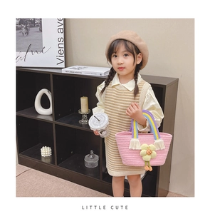 Détail du sac à main tissé rose pour enfants avec anse arc-en-ciel et fleur tricotée