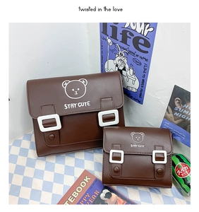 Detailed view of two brown PU leather school bags with cute bear print on plaid background