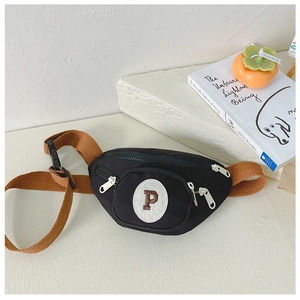Detail view of children's black canvas chest bag with brown strap and white zippers