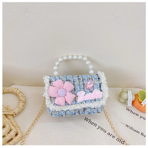 Detail of tweed girl's handbag with pink Barbie logo, pearl handle and gold chain strap