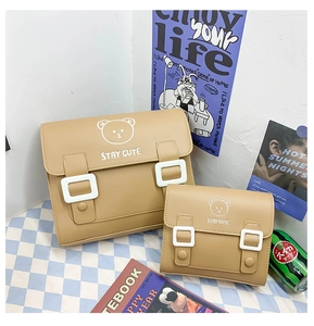Detail of two khaki PU mini backpacks featuring cute cartoon bear and Stay Cute print