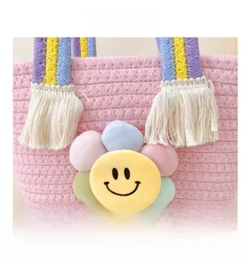 Détail d'un sac en coton tressé rose avec anse arc-en-ciel et pendentif tournesol peluche