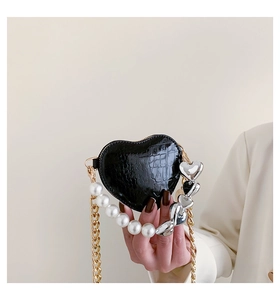 Gros plan du sac à main cœur noir avec texture crocodile et chaîne de perles