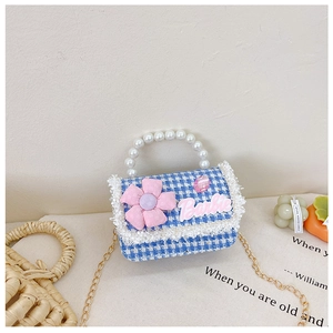 Detail of blue houndstooth girls' bag with pearl handle, pink flower, and gold chain
