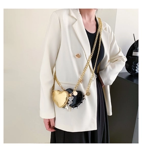 Détail de deux sacs en forme de cœur en doré brillant et cuir croco noir avec chaîne