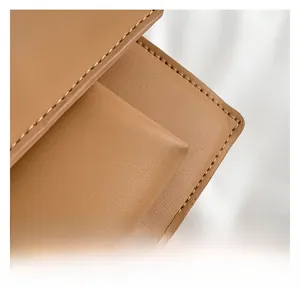 Close-up of caramel leather texture and neat stitching detail on a women's shoulder bag