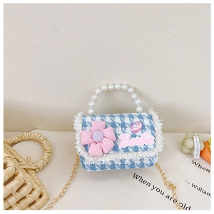 Macro shot of blue tweed houndstooth bag with white pearl handle and pink flower detail