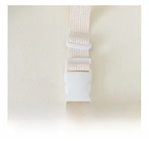Close-up detail of a white plastic buckle on a beige woven waist bag strap