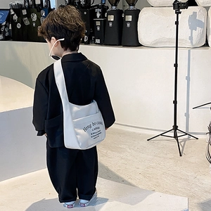 Kids minimalist white canvas crossbody bag with letter print shown on a child model