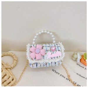 Detail of tweed children crossbody bag with pearl handle and pink flower decoration